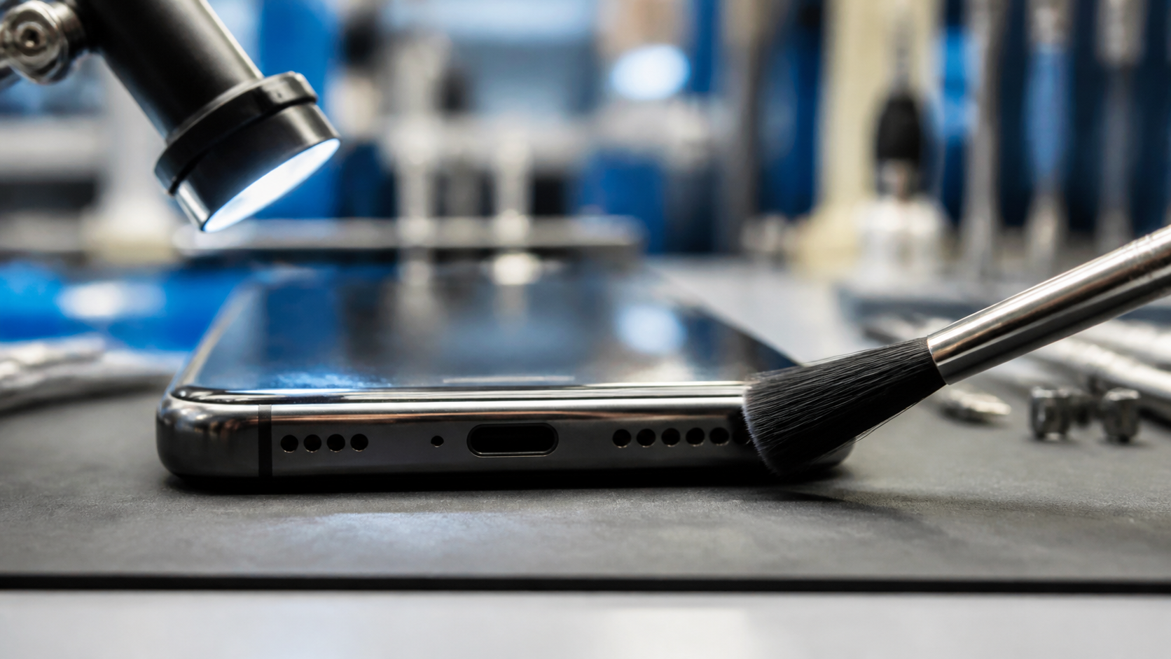 Smartphone speaker grille being inspected on a repair bench.